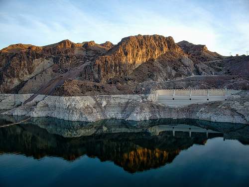 nature brown mountains beside body of water mountain